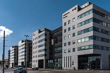 This picture shows the "IP-West" building in Budapest from the outside in daylight. You can see a street and behind it is the building.